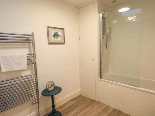 a bathroom with a shower and a small stool in front of a glass shower stall at Violet Cottage in Ambleside