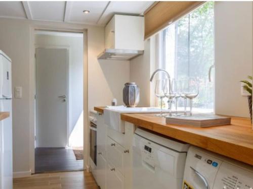 uma cozinha com armários brancos, um lavatório e uma janela em la p'tite maison em Waimes