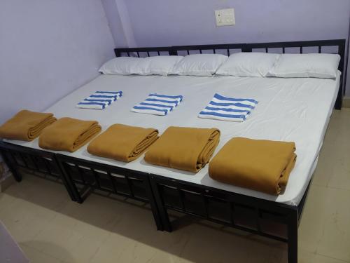 un letto con lenzuola bianche e blu e cuscini marroni di Ambai Deluxe Lodge a Kolhapur