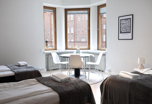 una camera con due letti e un tavolo con sedie di 2ndhomes Luxurious 144 m2 Stylish 3 Bedroom Center Apartment a Helsinki