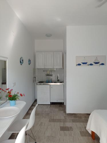 a white kitchen with white cabinets and a sink at Poseidon Studios Eressos in Skala Eresou