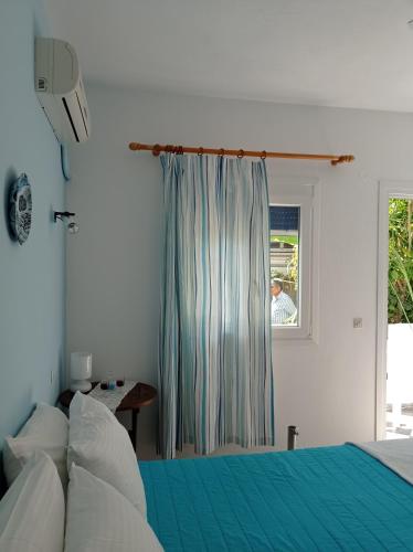 a bedroom with a blue bed and a window at Poseidon Studios Eressos in Skala Eresou