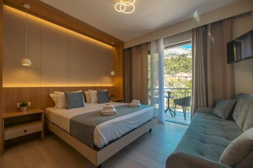 a bedroom with a bed and a couch and a balcony at Nicole Studios in Agia Effimia