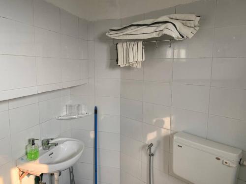 a white bathroom with a sink and a toilet at Kamil’s Studio Apartment in Lucknow