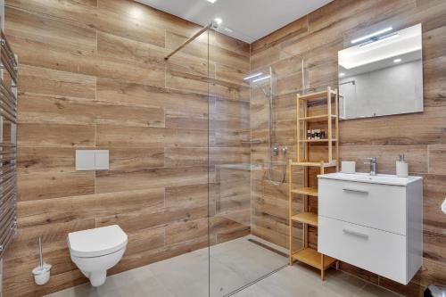 a bathroom with wooden walls and a toilet and a shower at SCANDIC Apartments Plešivec in Abertamy