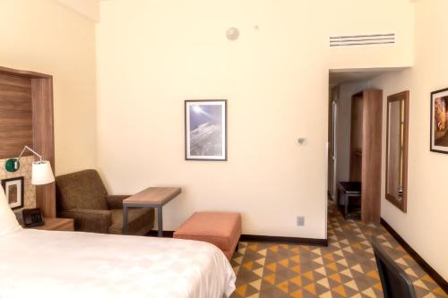 a hotel room with a bed and a chair at Holiday Inn Tlaxcala by IHG in Tlaxcala de Xicohténcatl