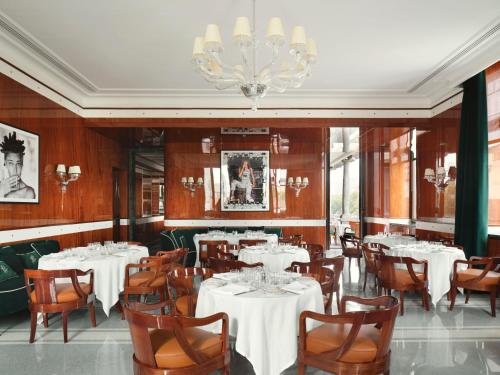 un ristorante con tavoli e sedie bianchi e un lampadario a braccio di Casa Cipriani Milano a Milano