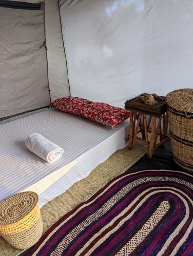 a bed in a tent with a table and baskets at Mawe Mawili in Tanga
