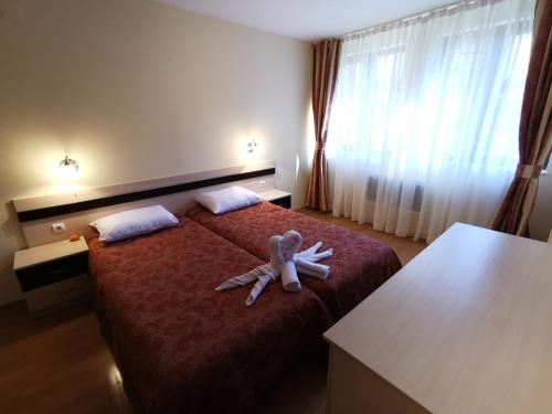 a teddy bear laying on a bed in a hotel room at Ski Area @ Apartment Rosea 205 @ Pamporovo in Pamporovo
