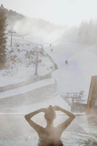 a man in the water in a bath tub with snow at ALMMONTE PRÄCLARUM SUITES Design Hotel in Wagrain