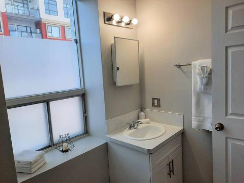 uma casa de banho com um lavatório, um espelho e uma janela em Modern Suite in Historic Bldg. Minutes to DT em Calgary