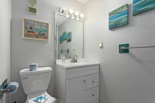 a bathroom with a toilet and a sink and a mirror at Pensacola Beach Front Emerald Waters in Pensacola Beach