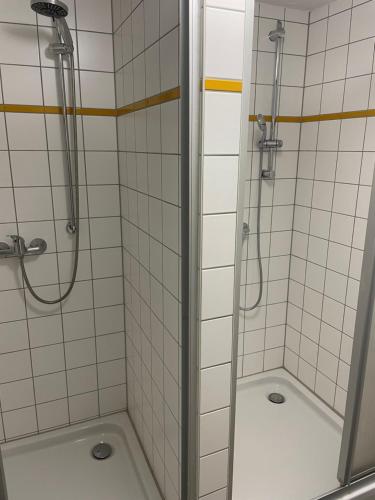 2 duchas en un baño con azulejos blancos en Pension Mathias Heilmann en Aschersleben