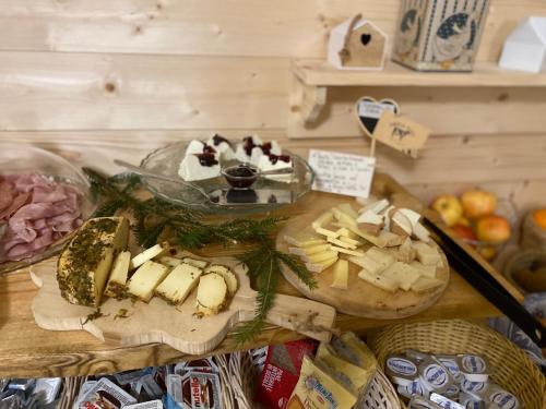 una mesa cubierta con queso y otros alimentos en una tabla de cortar en Dependance GRIMANI, en Ampezzo