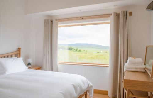 a bedroom with a bed and a large window at Finnan's Byre in Edinbane