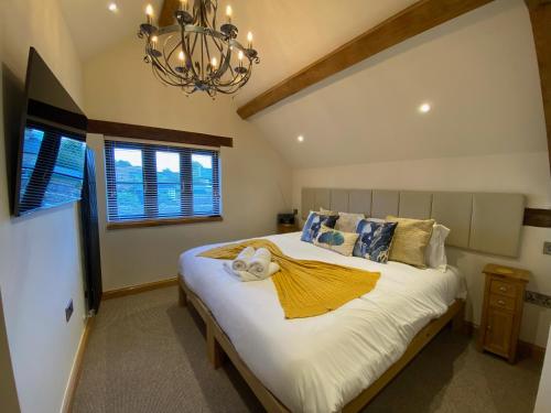 a bedroom with a large white bed with a chandelier at Folly Cottage & The Old Forge in Colerne