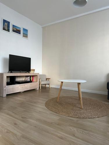 un salon avec une table et une télévision dans l'établissement Appartement Dunkerque proximité plage et centre ville, à Dunkerque