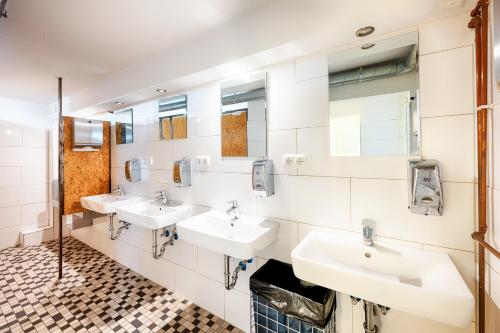 a bathroom with three sinks and two mirrors at Hostel Westlight in Hamburg
