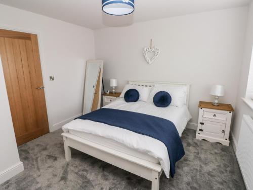 a bedroom with a white bed with blue pillows at LunaRoxx, 6 Meadow Gardens, Kilgetty in Kilgetty
