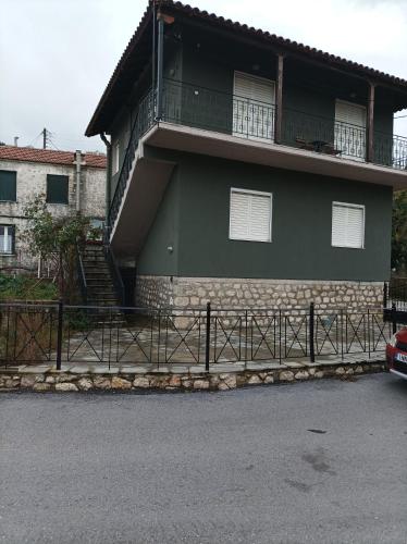 a green house with a balcony on the side of it at ELLI΄S HOUSE ΣΥΓΧΡΟΝΟ ΣΠΙΤΙ ΣΤΑ ΠΡΑΜΑΝΤΑ in Pramanta