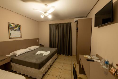 een hotelkamer met een bed en een televisie bij Pousada Villa da Mata in São Miguel Arcanjo