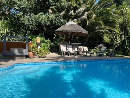 a swimming pool with a table and chairs and an umbrella at Santika Villa Stellenbosch in Stellenbosch
