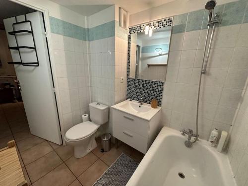 La salle de bains est pourvue de toilettes, d'un lavabo et d'une baignoire. dans l'établissement L'escale de Neauphle aux portes de Versailles, à Neauphle-le-Château
