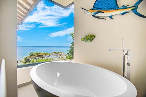 a bathroom with a tub and a window with a fish on the wall at Paradise Chalets Yoga & Wellness in Takamaka