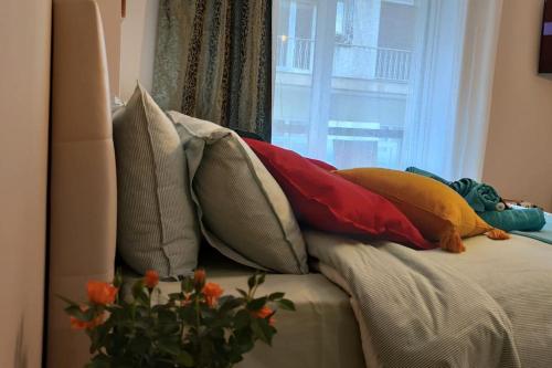 a pile of pillows on a bed with a window at Cozy studio, 1min from Kamara in Thessaloniki