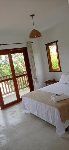 um quarto com uma cama e uma grande janela em Pousada Aroeira em Itaúnas