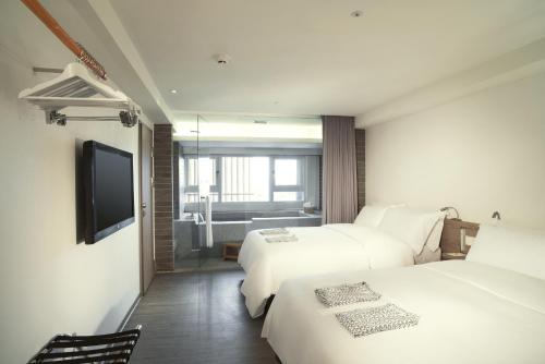 a hotel room with two beds and a flat screen tv at Just Sleep Jiao Xi in Jiaoxi