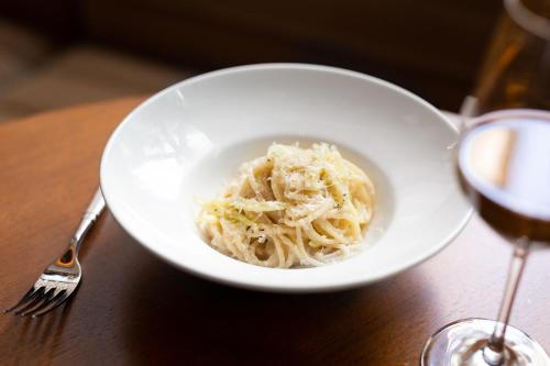 a bowl of pasta on a table next to a glass of wine at LUMA Hotel - Times Square in New York