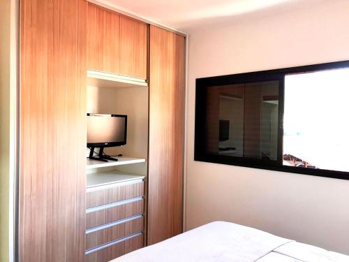 1 dormitorio con 1 cama, TV y espejo en Apto c otima localizacao e WiFi Pocos de Caldas MG, en Poços de Caldas