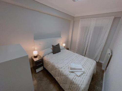a white bedroom with a bed and a window at Piso Atares Calle Alfonso in Zaragoza