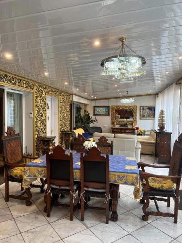 une salle à manger avec une table, des chaises et un lustre dans l'établissement Villa Baroque, à Pierrefitte-sur-Seine