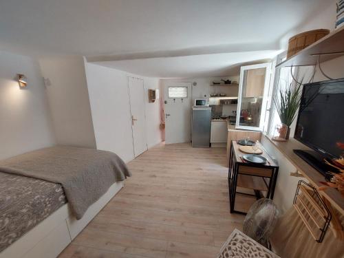 Cette petite chambre comprend un lit et une télévision. dans l'établissement Hyères studio refait à neuf dans la cité médiévale, à Hyères