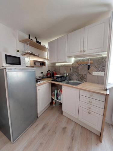 une cuisine avec des armoires blanches et un réfrigérateur en acier inoxydable dans l'établissement Hyères studio refait à neuf dans la cité médiévale, à Hyères