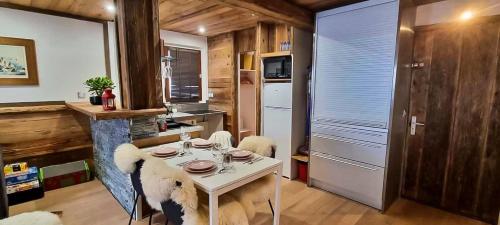 uma cozinha com uma mesa branca e cadeiras num quarto em Logement à Megève avec Jardin em Megève