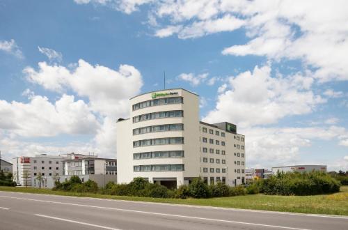 a white building on the side of a road at Holiday Inn Express München Messe by IHG in Feldkirchen