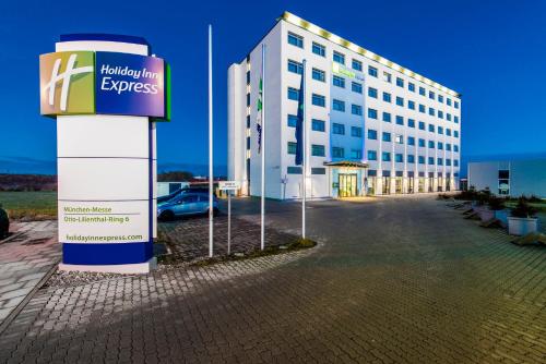 a large white building with a sign in front of it at Holiday Inn Express München Messe by IHG in Feldkirchen