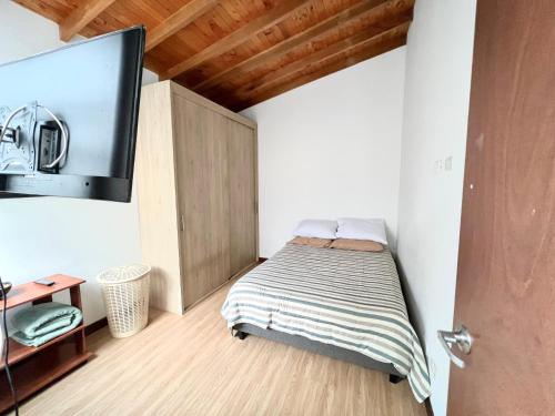 Schlafzimmer mit einem Bett und einem Flachbild-TV in der Unterkunft Cómodo apartamento completo en Envigado in Envigado