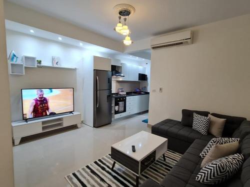 Diar El Rabwa Modern Apartment في شرم الشيخ: غرفة معيشة مع أريكة وتلفزيون بشاشة مسطحة