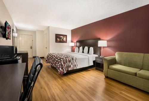 a hotel room with a bed and a couch at Red Roof Inn & Suites Knoxville East in Knoxville