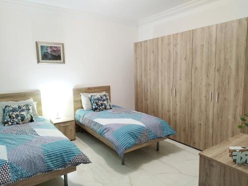 a bedroom with two beds and wooden cabinets at Large and modern apartment in the centre of Malta in Mosta