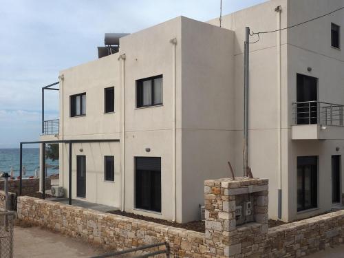 a white building with the ocean in the background at Melissinos Beachfront Apartments in Kómi