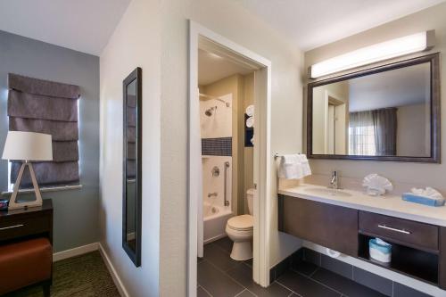 a bathroom with a sink and a toilet and a mirror at Sonesta ES Suites Dulles Airport in Herndon