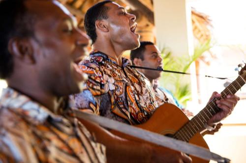a group of men playing guitar and singing at Outrigger Fiji Beach Resort in Korotogo