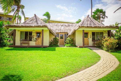 a small yellow house with a grass yard at Outrigger Fiji Beach Resort in Korotogo