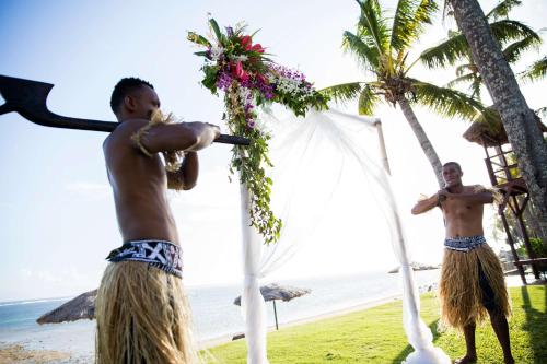 a couple of men standing on the beach at Outrigger Fiji Beach Resort in Korotogo