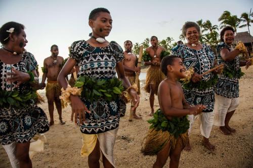 a group of people walking on the beach with bananas at Outrigger Fiji Beach Resort in Korotogo
